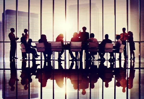 Conference room table with people sitting and standing around